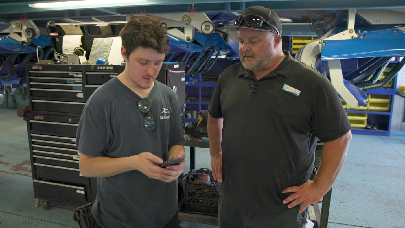 Technician showing a flagged finding on his phone to a maintenance lead