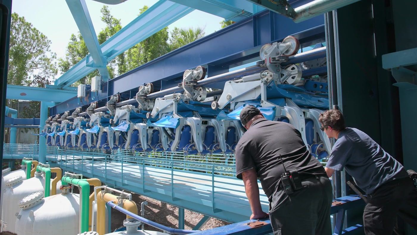 Technicians inspecting a coaster train in the station before opening