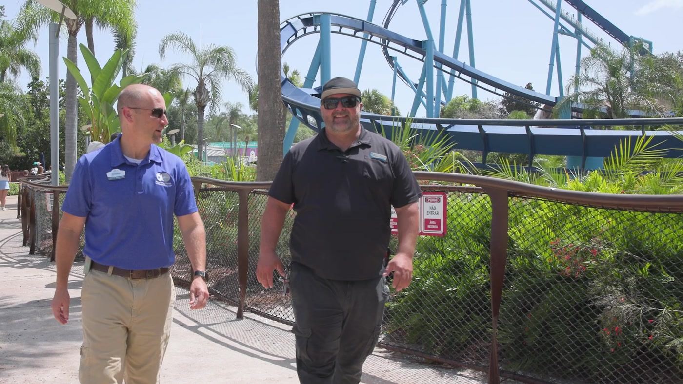 Maintenance leaders walking through the park with a coaster in the background